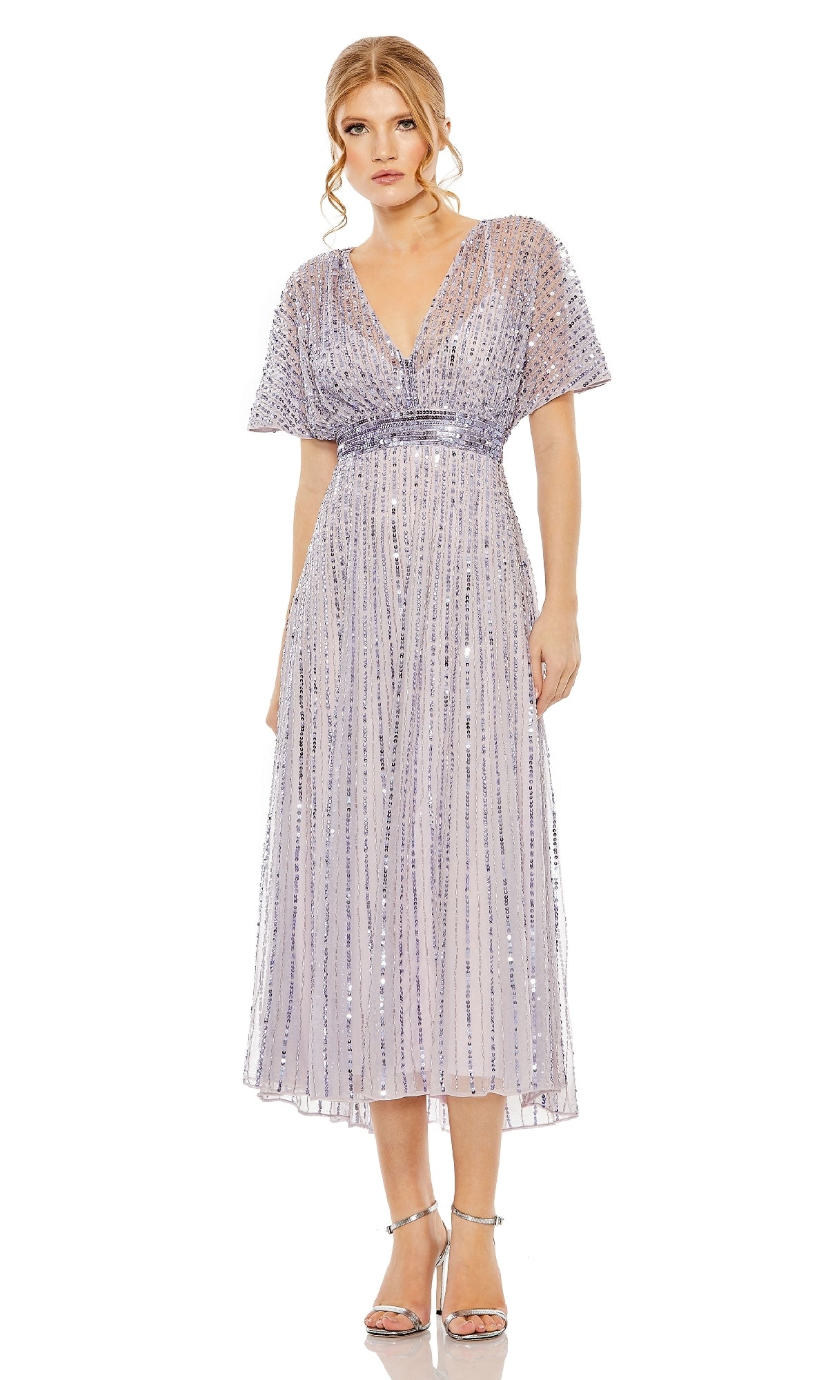 A woman wears the Mac Duggal 14007 short sequin wedding-guest dress in light purple with flutter sleeves, paired with silver heels—a chic semi-formal choice.